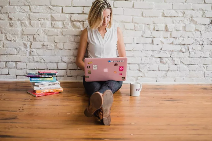 woman typing on a laptop with books nearby