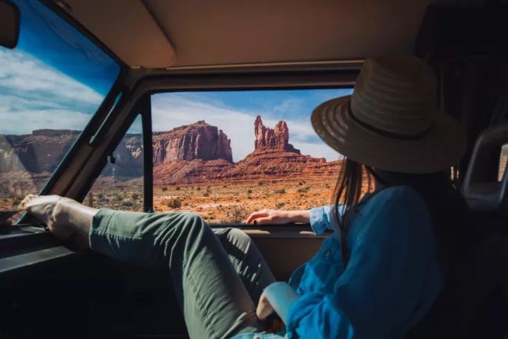 Girl in a car looking outside from the window  wearing blue shirt and green pent