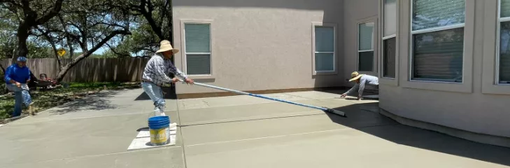 Concrete patio construction in San Antonio, TX with workers pouring cement and smoothing the surface.