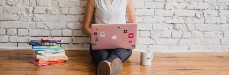 woman typing on a laptop with books nearby