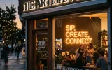 Warmly lit storefront of The Artisan Hub cafe with a glowing neon sign reading Sip Create Connect and people socializing inside during the evening