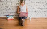 woman typing on a laptop with books nearby